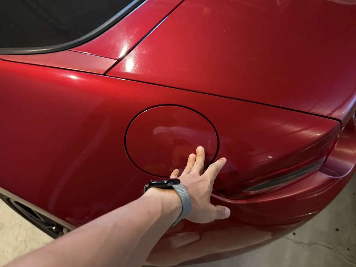 車体左後方の丸い給油口フタを手で押している